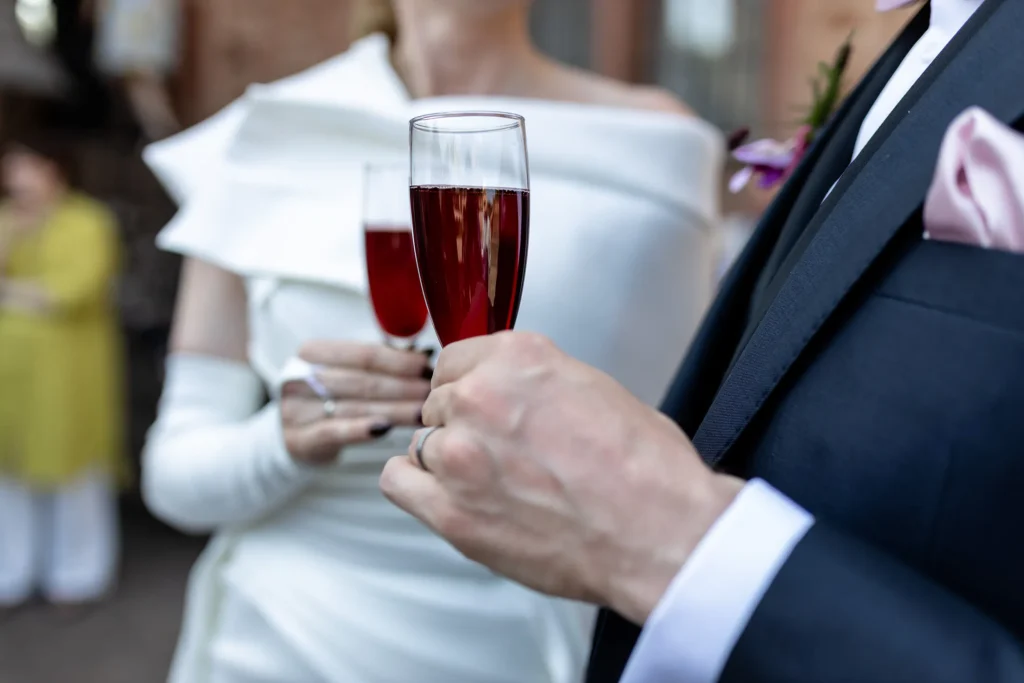 Hochzeitsfotograf Trier Luxemburg - Nahaufnahme von zwei Sektgläsern, die von Braut und Bräutigam gehalten werden.