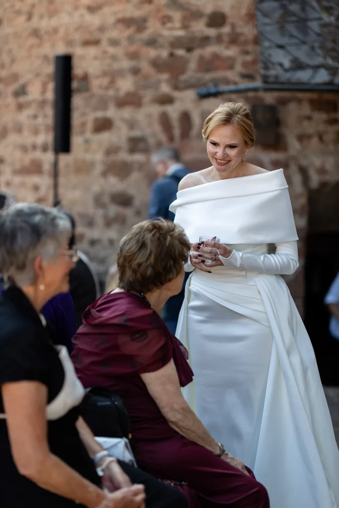 Hochzeitsfotograf Trier Luxemburg - Die Braut unterhält sich auf dem Vorhof von Schloss Hamm mit ein paar Gästen.