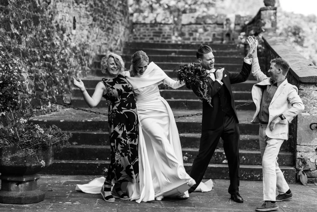 Hochzeitsfotograf Trier Luxemburg - Ein etwas anderes Gruppenfoto mit Brautpaar: Die Braut fällt fast hin und der Bräutigam macht Spass-Kämpfe mit seinem Freund