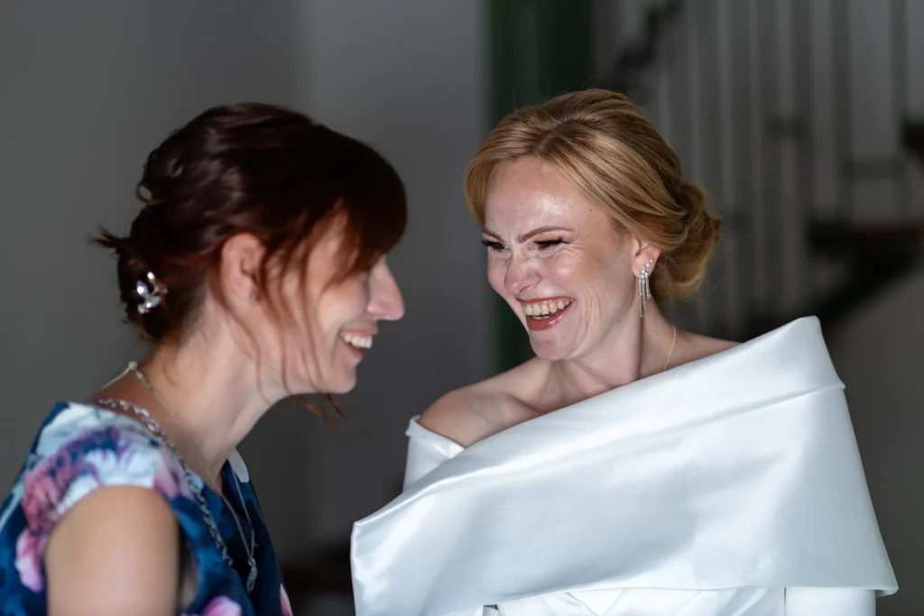 Hochzeitsfotograf Trier Luxemburg - Braut und Trauzeugin lachen herzlich miteinander beim Getting Ready